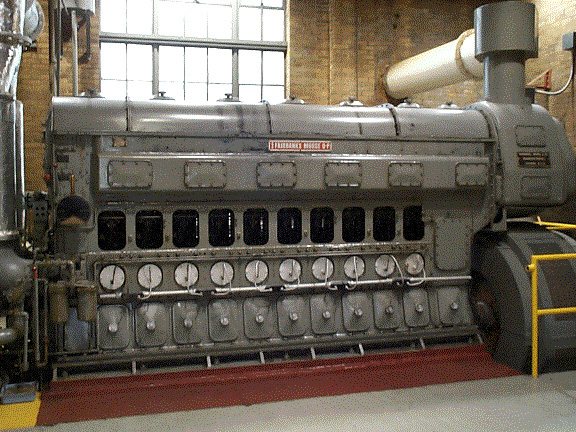 Close-up of a large gray engine with a row of gauges along its side.
