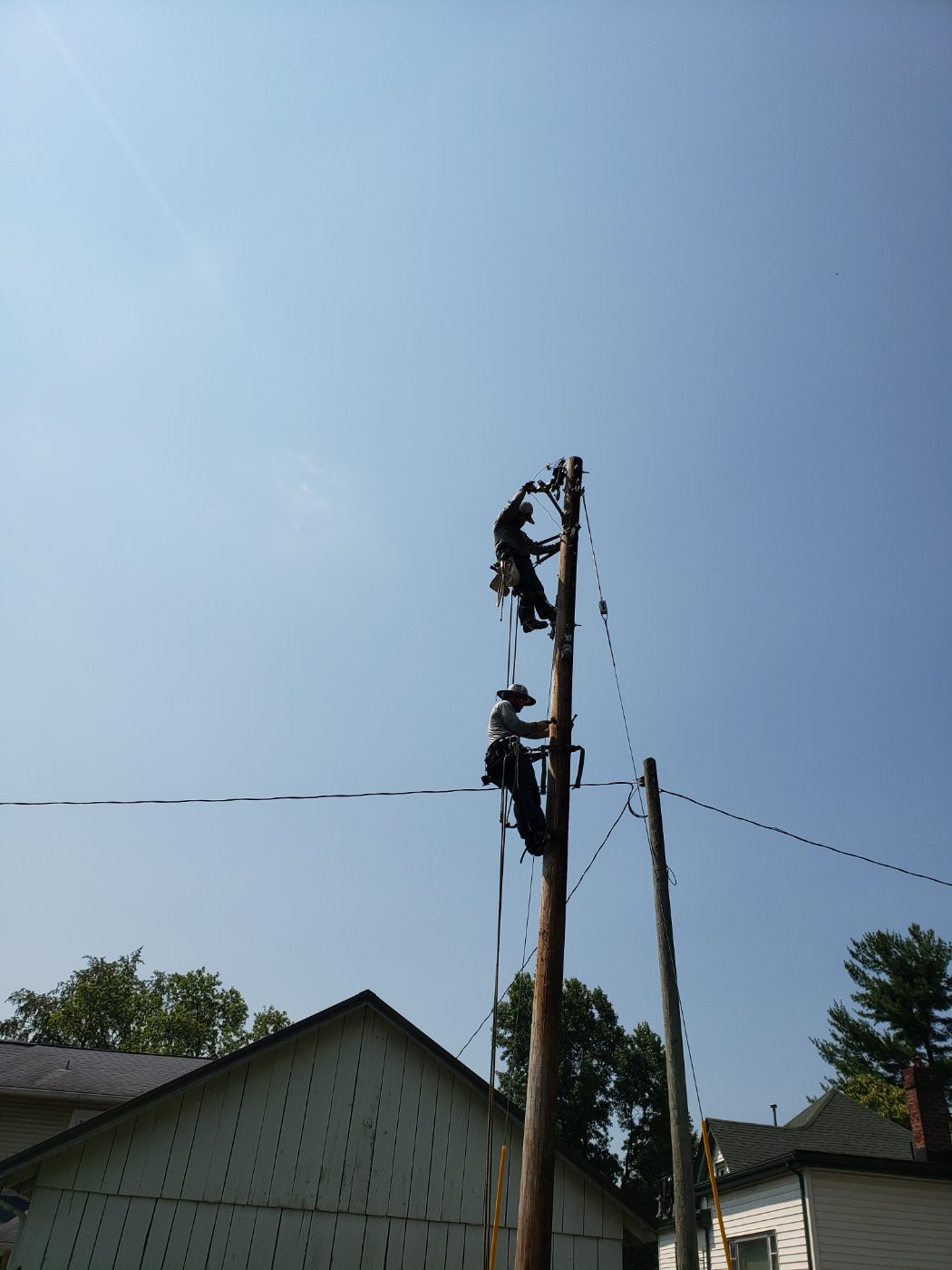 Two Paris Electric line workers climbing a utility pole.