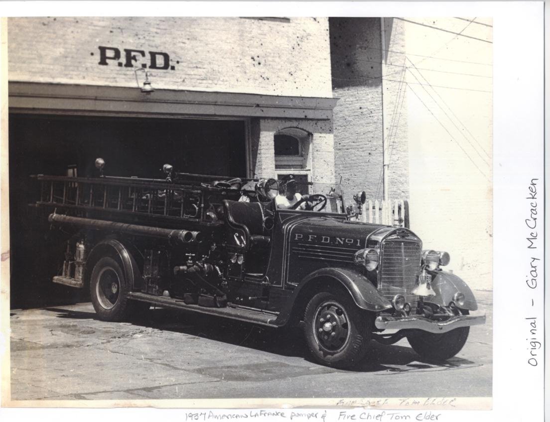 Black-and-white photo of a 1937 Paris Fire Department truck lettered P.F.D. No. 1 in front of a station bay marked P.F.D.